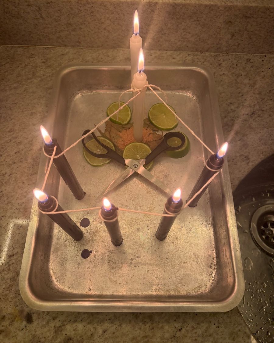 Ritual de corte de laços: cinco velas ligadas por barbante em forma de pentagrama, tesoura aberta e fatias de limão